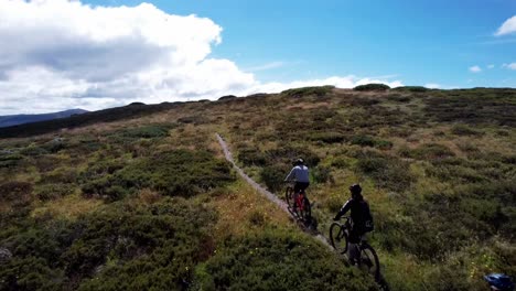 Drone-following-mountain-bike-riders-going-up-a-mountain-heading-to-the-peak
