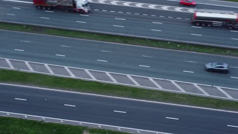 Aerial-view-overhead-traffic-vehicles-driving-on-busy-M62-UK-motorway-lanes-Birdseye-pan-left-shot