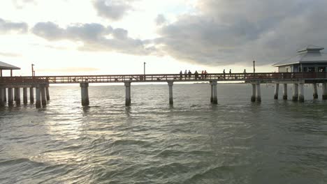 Aerial-view-people-walking-at-Fort-Myers-iconic-Pier-during-sunset,-Florida
