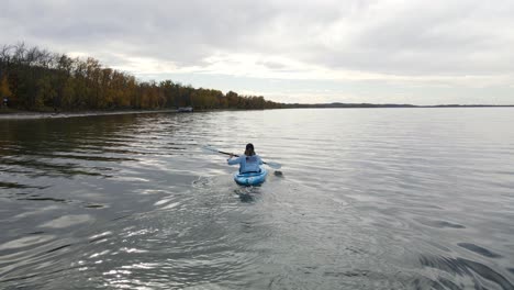 Young-woman-kayaking-on-a-large,-blue-lake-in-Alberta,-Canada