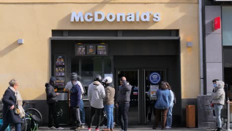 A-group-of-food-delivery-drivers-stand-outside-of-a-McDonalds,-waiting-for-their-orders