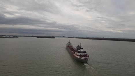 Long-cargo-vessel-with-Canada-flag-in-Detroit-river,-aerial-orbit-view