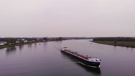 Aerial-Flying-View-Of-Monika-Inland-Tanker-Ship-Navigating-Oude-Maas-On-Cloudy-Day