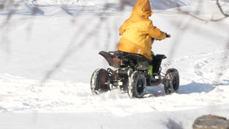 boy-driving-mini-atv-in-snow-on-bright-winter-day-in-Lapland