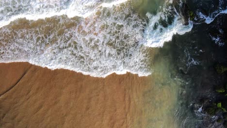 waves-breaking-at-black-rocks-in-Geriba-Beach-in-Buzios,-Brazil,-Aerial-top-down-view