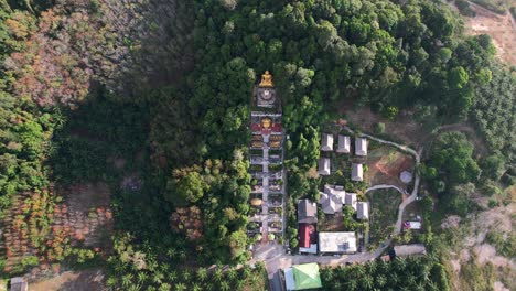aerial-drone-of-a-unique-temple-with-a-golden-buddha-on-a-mountain-surrounded-by-coconut-trees-in-Ao-Nang-Krabi-Thailand