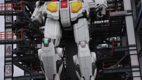 4k-Huge-Robot-Gundam,-Close-Tilt-Shot-over-Factory-Display