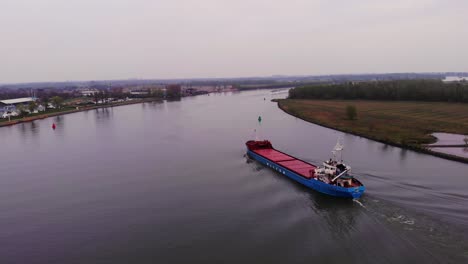 Aerial-Dolly-Following-Stern-Of-Torpo-Cargo-Ship-Approaching-Bend-On-Oude-Maas-Near-Barendrecht-On-Overcast-Day