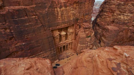 The-Treasury-Khaznet-at-Petra,-historic-UNESCO-heritage-site-carved-into-sandstone-in-Jordan-seen-from-a-viewpoint-above