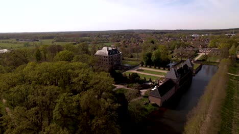Descending-aerial-showing-surrounding-lane-and-moat-of-Dutch-painterly-picturesque-castle-Amerongen-on-a-bright-sunny-day-with-meadows-in-the-foreground