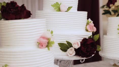 Multiple-Round,-Layered-Wedding-Cakes-on-a-Table-Decorated-with-White-Frosting-and-Pink-and-Maroon-Flowers-1080p-60fps