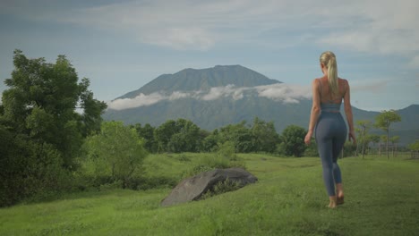 Mujer-Rubia-Serena-Caminando-Hacia-La-Roca-Para-Ver-Mejor-El-Volcán-Agung