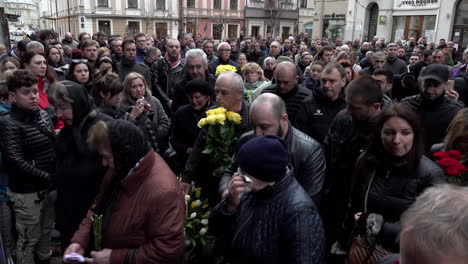Masses-of-people,-some-carrying-flowers,-move-into-the-entrance-of-the-Church-of-the-Most-Holy-Apostles-Peter-and-Paul-to-pay-their-respects-at-the-funeral-of-fallen-Ukrainian-soldiers