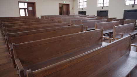 Old-Wooden-Pews-in-Empty-Hall,-Background-Pan-Shot