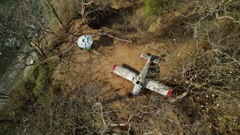 Abandoned-small-airplane-stuck-on-the-top-of-a-hill-by-the-coast-in-Costa-Rica,-province-of-Guanacaste-4K-aerial-drone-from-above-pan-up