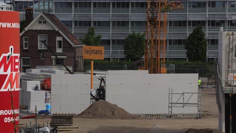 Interior-supporting-home-walls-being-build-by-construction-workers-with-small-crane-and-prefab-large-white-bricks-in-construction-site-part-of-urban-development-plan-Noorderhaven-neighbourhood