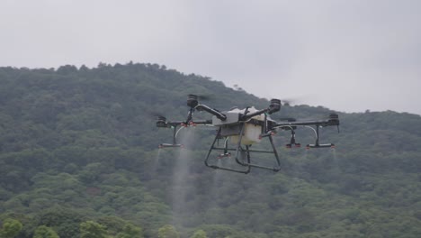 Agricultural-drone-flying-in-the-air,-spraying-liquid-pesticides-over-green-rice-field-in-China-on-a-cloudy-day
