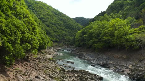 Puente-Hozukyo-Y-Río-Katsura,-Retroceso-Aéreo-En-Arashiyama,-Kyoto,-Japón