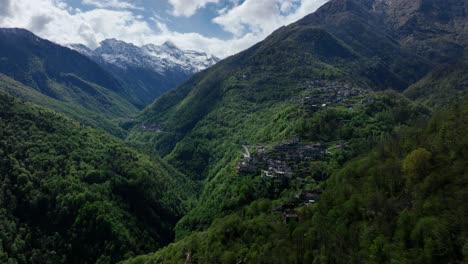 Vuelo-Sobre-El-Aislado-Pueblo-De-Los-Alpes-Italianos-En-Una-Exuberante-Cresta-Montañosa