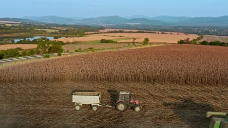 Aerial-flyover-of-harvesting-agricultural-machinery-in-Bulgarian-sunflower-fields-with-Elena-balkans-hills-in-background