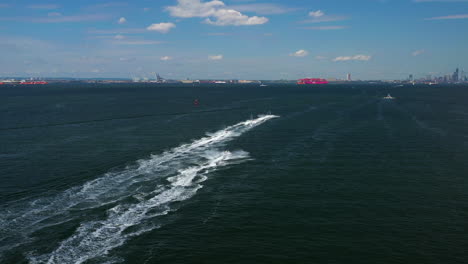 aerial-chase-of-a-group-of-jet-ski-riders-on-the-waters-between-Brooklyn---Staten-Island,-New-York,-moving-towards-New-York-City-and-the-horizon