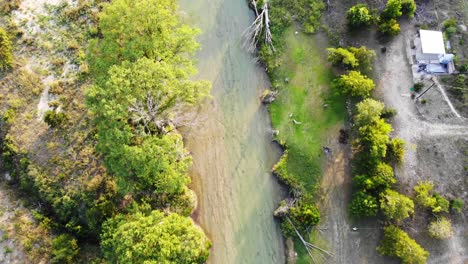 Top-down-view,-quickly-flying-up-river-at-sunset,-water-is-a-deep-green-blue