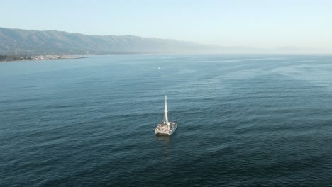 Circular-aerial-near-sailboat-full-with-tourists-on-cruise-during-a-beautiful-sunset-on-the-Pacific-ocean-near-the-coast-of-Santa-Barbara,-California,USA