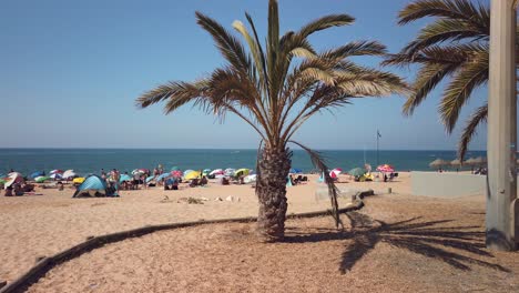 Strand-Von-Quarteira-An-Der-Algarve-Portugal-Mit-Sonnenschirmen,-Sonnenanbetern-Mit-Meer-Und-Sand-Und-Herrlichem-Sonnenschein
