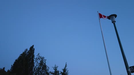 Slowmotion-view-landscape-zooming-view-into-the-Canada's-flag-while-wind-blowing-in-sunset-sky-time