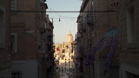 Narrow-street-with-flags-in-Malta,-overlooking-one-of-the-three-cities