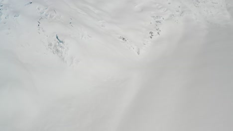 4K-Drohnenaufnahmen,-Die-Vorwärts-Fliegen-Und-Vom-Gletscher-Mit-Gletscherspalten-Zu-Gewaltigen,-Imposanten-Bergen-Mit-Eisfällen-Hinaufschwenken