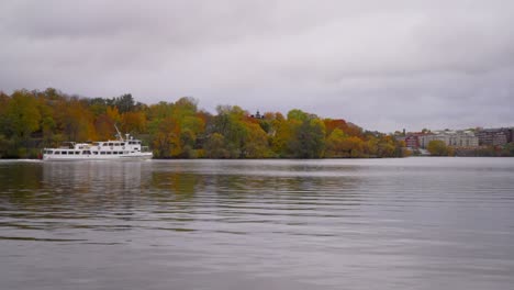 a-white-small-ferry-is-going-from-one-island-to-another-in-Stockholm-in-the-autumn-with-colorful-trees