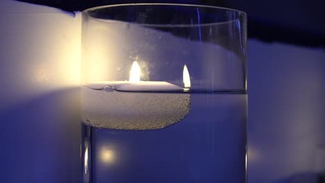 Eine-Wunderschöne-Blaue-Kerze,-Die-Brennt-Und-Deren-Licht-Sich-An-Der-Wand-Spiegelt