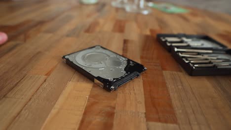 Man-changes-screws-and-working-on-a-hard-drive-that-lies-on-a-wooden-table