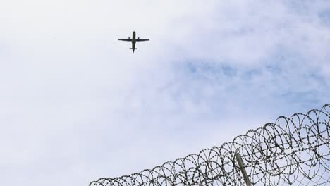 Plane-Taking-Off-Over-Barbed-Wire-on-a-Cloudy-Background