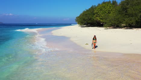 sandy-sea-beach,-Black-sea,-a-girl-walking-on-the-wet-sand-in-the-bikini,-with-snorkeling-mask-on-the-head-and-fins-in-hand
