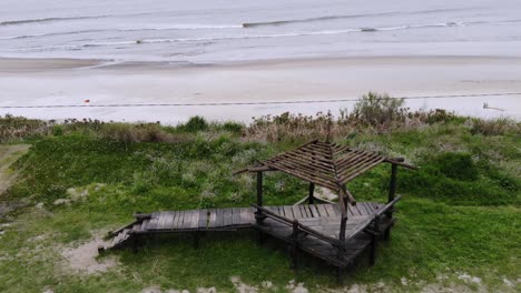 Aerial-video-of-a-wooden-structure-located-on-the-coast-with-the-beach-behind