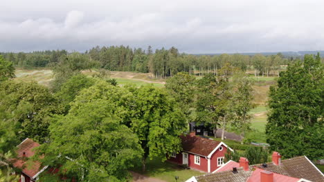 Aerial-shot-towards-hilly-golf-course-in-Sweden-surrounded-by-trees