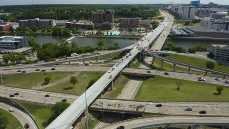 Aerial-Perspective-of-Cars-Driving-Along-Old-Highway---Pan-Up-to-Reveal-City-Skyline