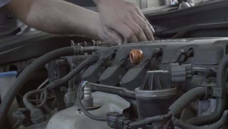 Fixed-shot-of-a-mechanics-hands-as-the-works-on-a-car-engine