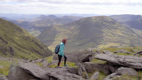 Lateral-tracking-shot-of-a-happy-girl-hiking-and-walking-on-the-high-mountain-trail-outdoor-in-nature-in-Ireland-at-Mcgillycuddy-Reeks-in-4K