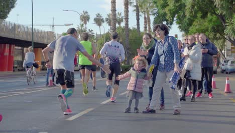 Adorable-kid-giving-high-fives-to-marathon-runners-in-Malaga,-Spain,-crowd-cheering-for-sportists