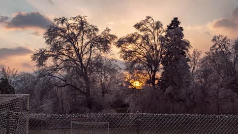 TIME-LAPSE:-A-beautiful-sunset-above-a-frozen-soccer-field-with-large-white-icy-trees-in-the-distance