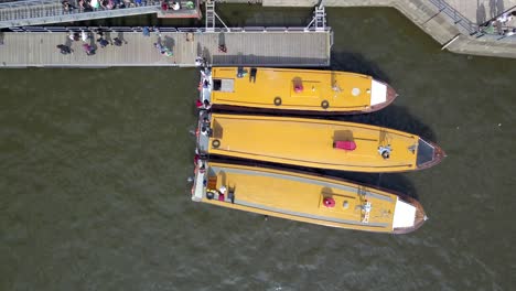 Aerial-top-down-of-people-getting-down-of-three-commuter-boats-docked-side-by-side