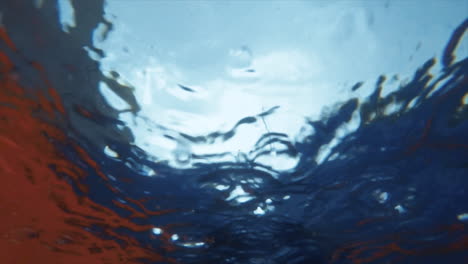 Abstract-and-hypnotic-slow-motion-shot-of-raindrops-falling-into-a-pool-seen-from-underwater