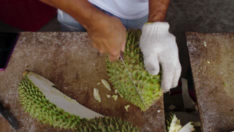 Asian-man-cuts-and-peels-durian-in-glove