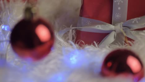 Weihnachtsgeschenk-Mit-Roten-Kugeln,-Lichtern-Und-Bandhintergrund