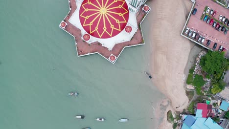 Tanjung-Bunga-floating-mosque-is-seen-from-above-with-massive-red-and-yellow-dome,-Aerial-drone-pan-up-from-above-view