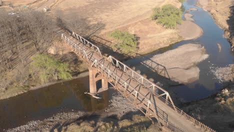 aerial-shot-of-a-mountain-biker-crossing-an-old-steel-bridge