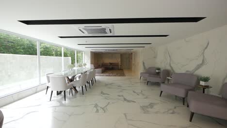 White-Meeting-Room-with-Marble-Pattern-Decoration,-Furnished-with-Long-Glass-Table,-Grey-and-White-Armchairs